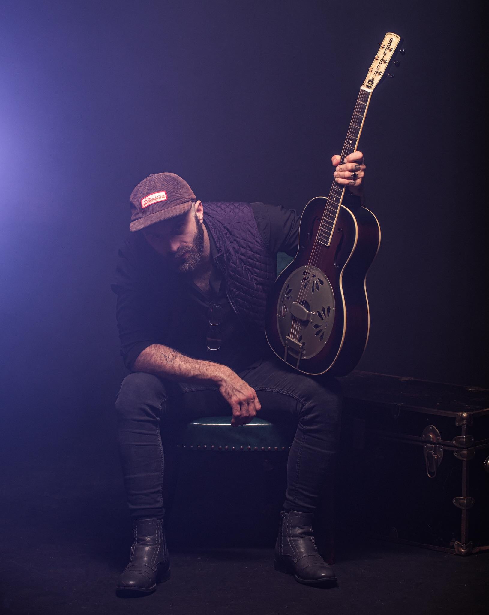 Joshua T. Hester with a resonator guitar in purple light